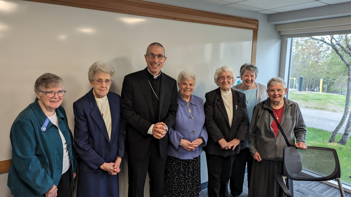 Bishop standing with six nuns
