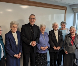 Bishop standing with six nuns