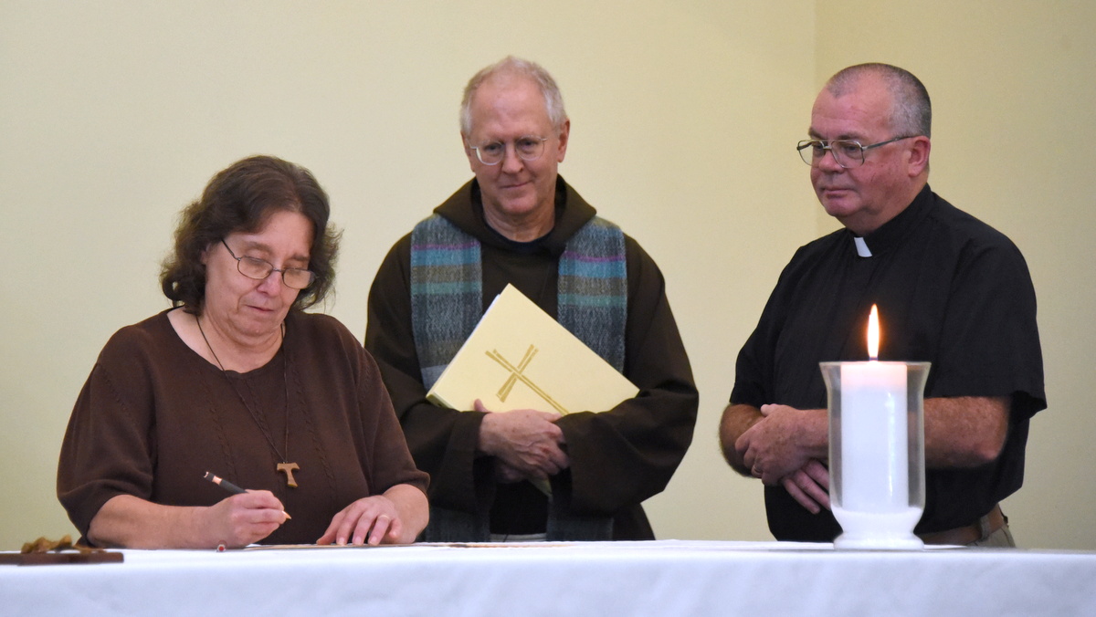 Lynette Dobbs signs documents establishing the Heart of St. Francis Fraternity