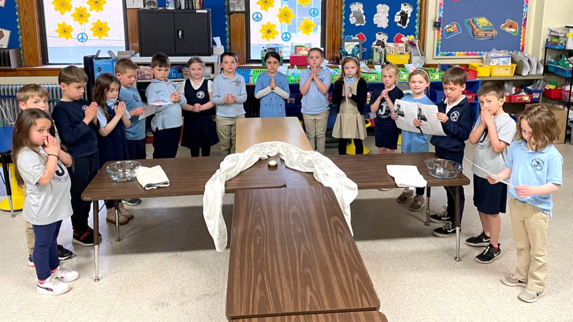 St. James School students surround tables that form a cross.