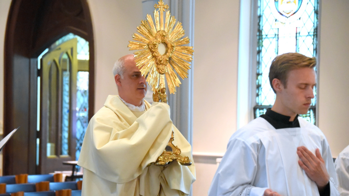 Father Seamus Griesbach carrying the Blessed Sacrament in a eucharistic procession.