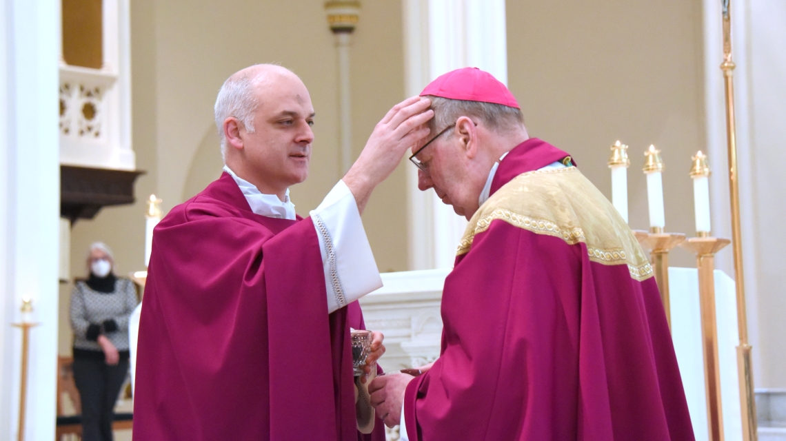 Father Seamus Griesbach marks the forehead of Bishop Robert Deeley with ashes.