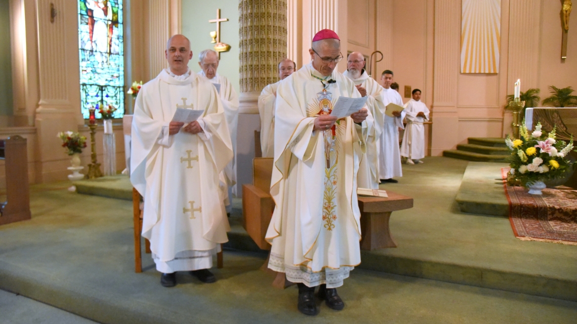Bishop Ruggieri with Father Seamus Griesbach to his left and other priests behind him.