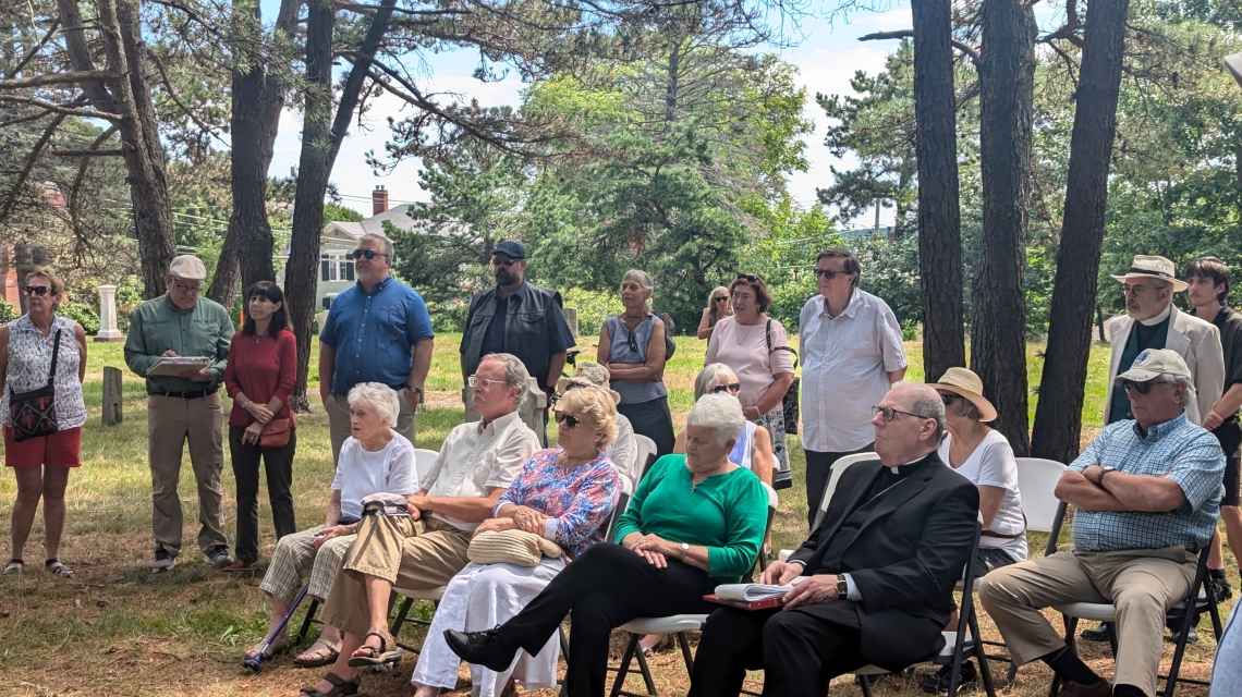 Group sits in a wooded cemetery.