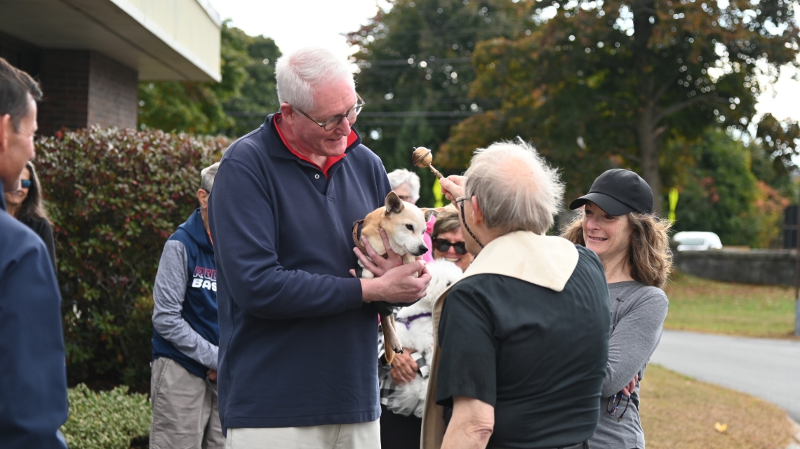 Father Michalowski sprinkles a dog with holy water.