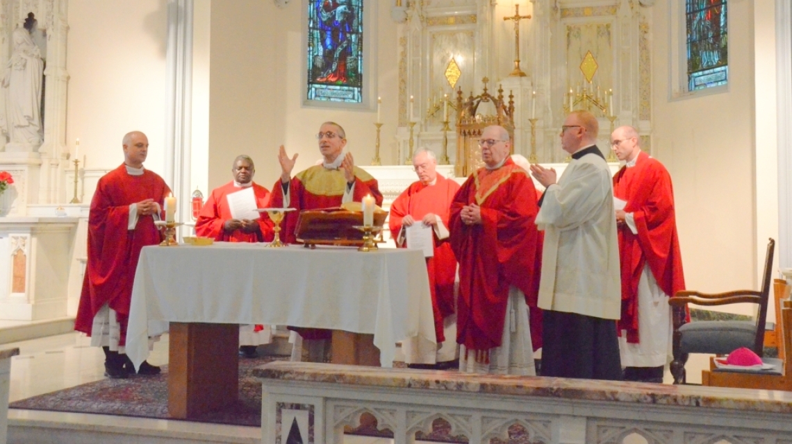 Bishop Ruggieri, Bishop Deeley, and priests at the alter in red vestments