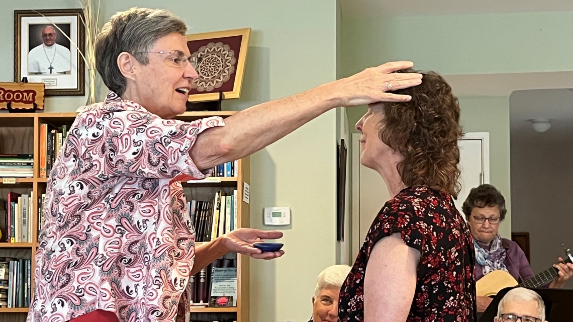 Sister Judy Donovan anoints the head of Toni Fredette.