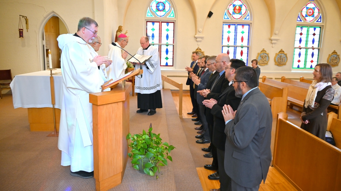 Deacon candidates stand before Bishop Ruggieri with Deacon Peter Bernier in the foreground