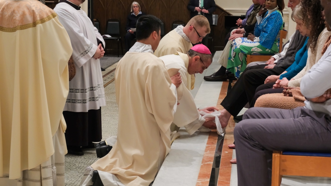 Bishop kneeling and washing feet on the altar.