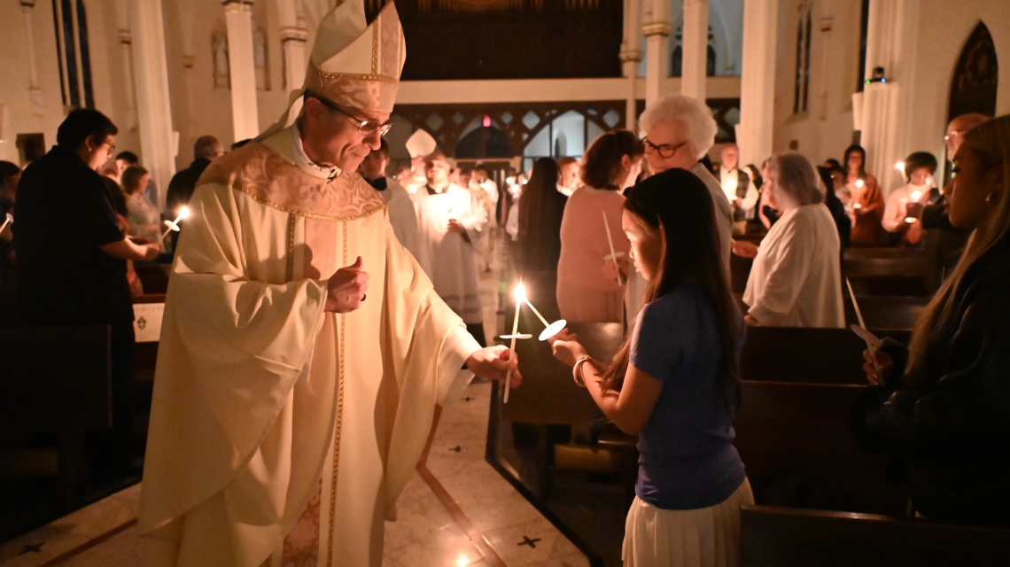 Bishop lights the candle for a young woman.