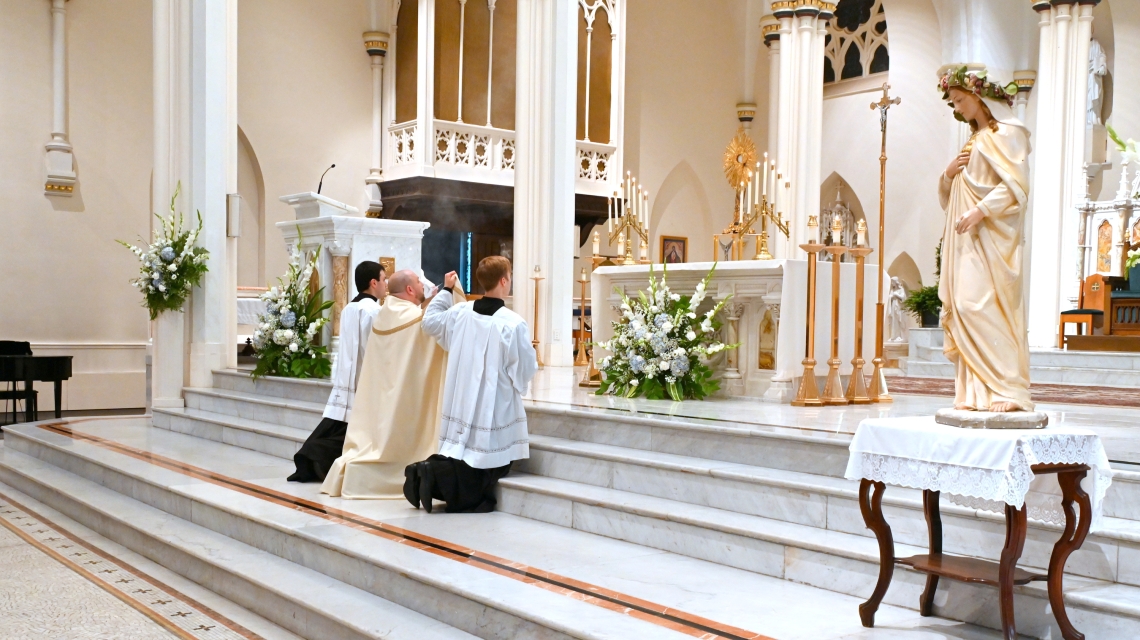 Father Brad Morin and two altar servers incensing the Blessed Sacrament.