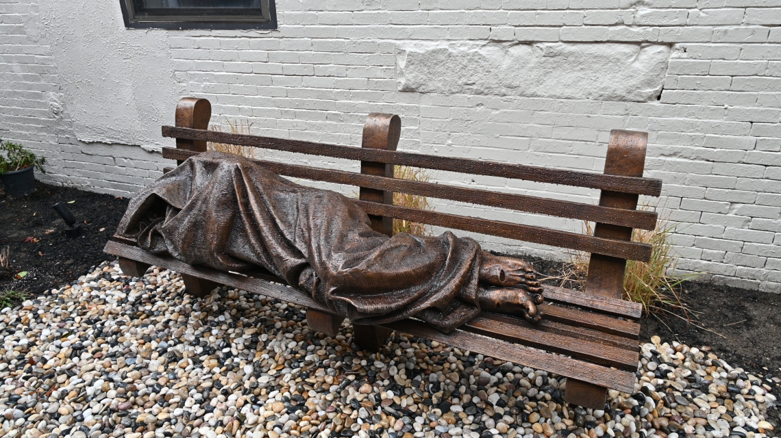 sculpture of mass sleeping on a bench
