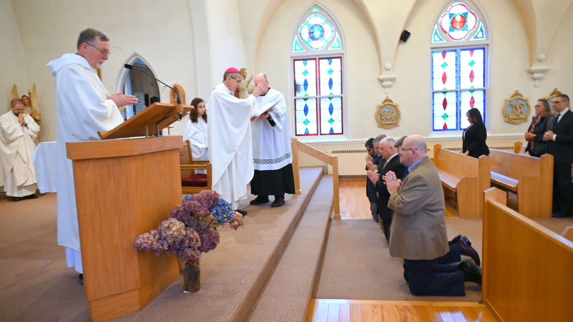 Bishop Ruggieri prays over the kneeling deacon candidates.