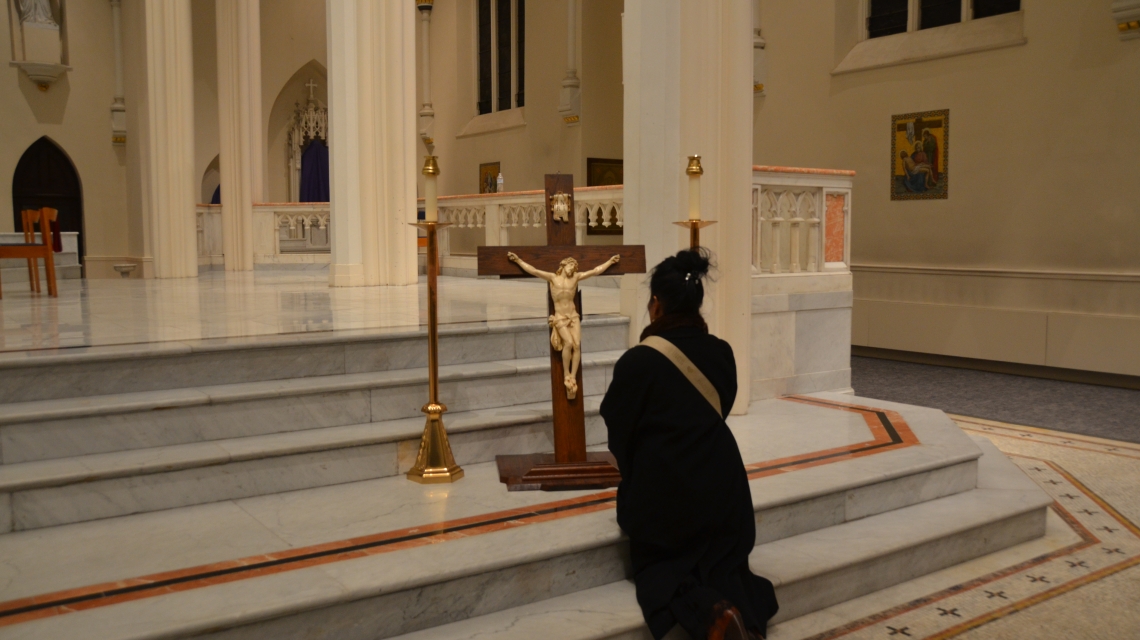 Woman kneels in from of the cross