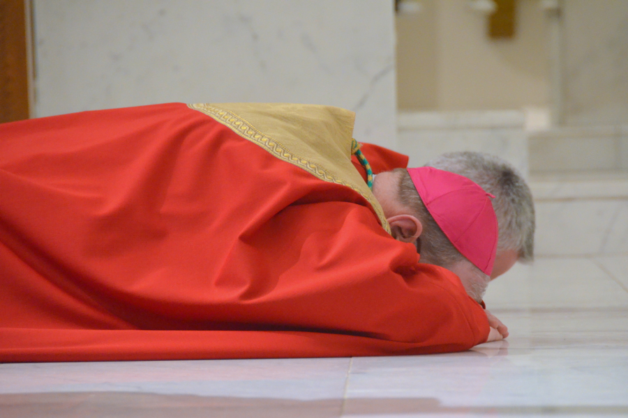 Bishop Deeley prostrates himself before the cross.