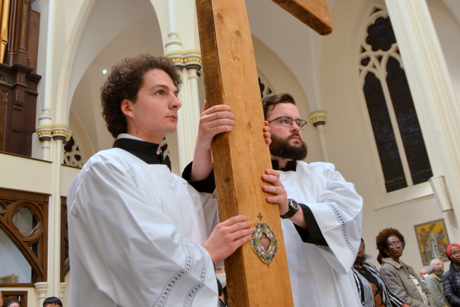 Altar servers carry the cross.