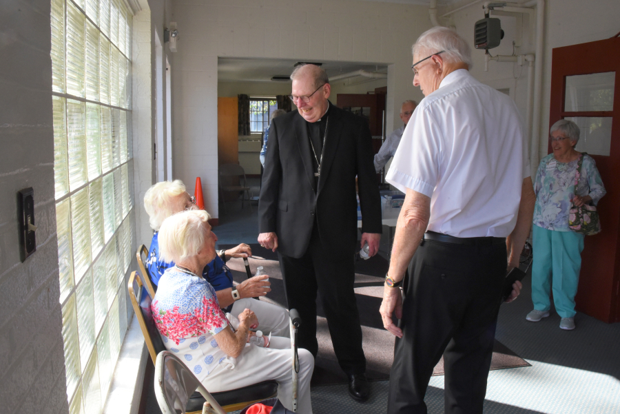 Bishop Deeley chats with two women who use the food closet.