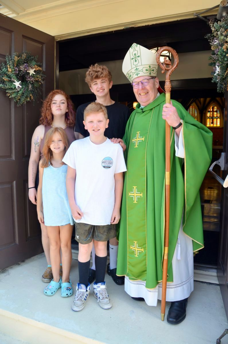Bishop Deeley with a family outside Star of the Sea Church in York Beach