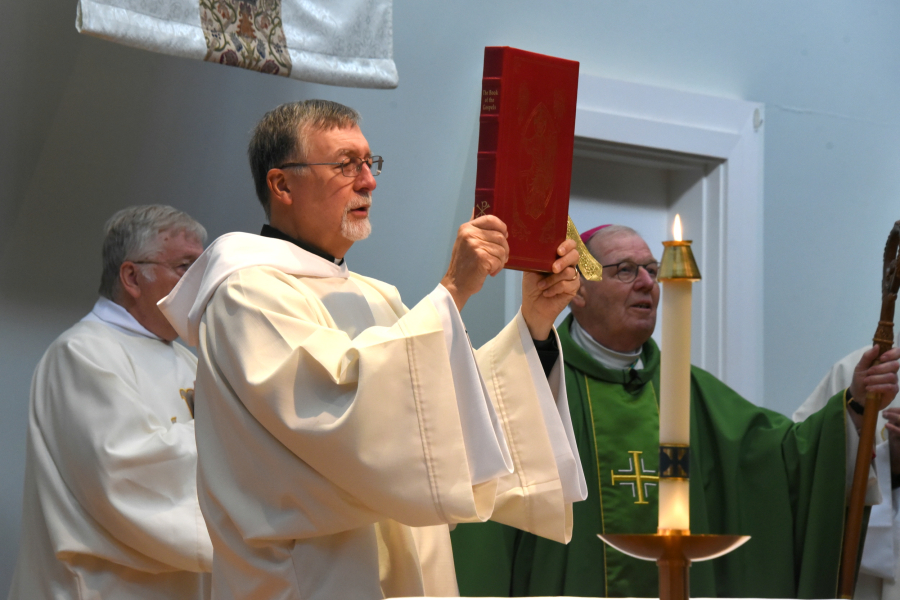 Deacon Peter Bernier holds up the Book of the Gospels.