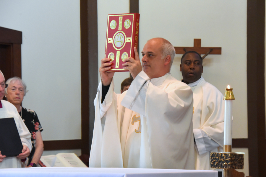 Father Seamus Griesbach holds up the Book of the Gospels