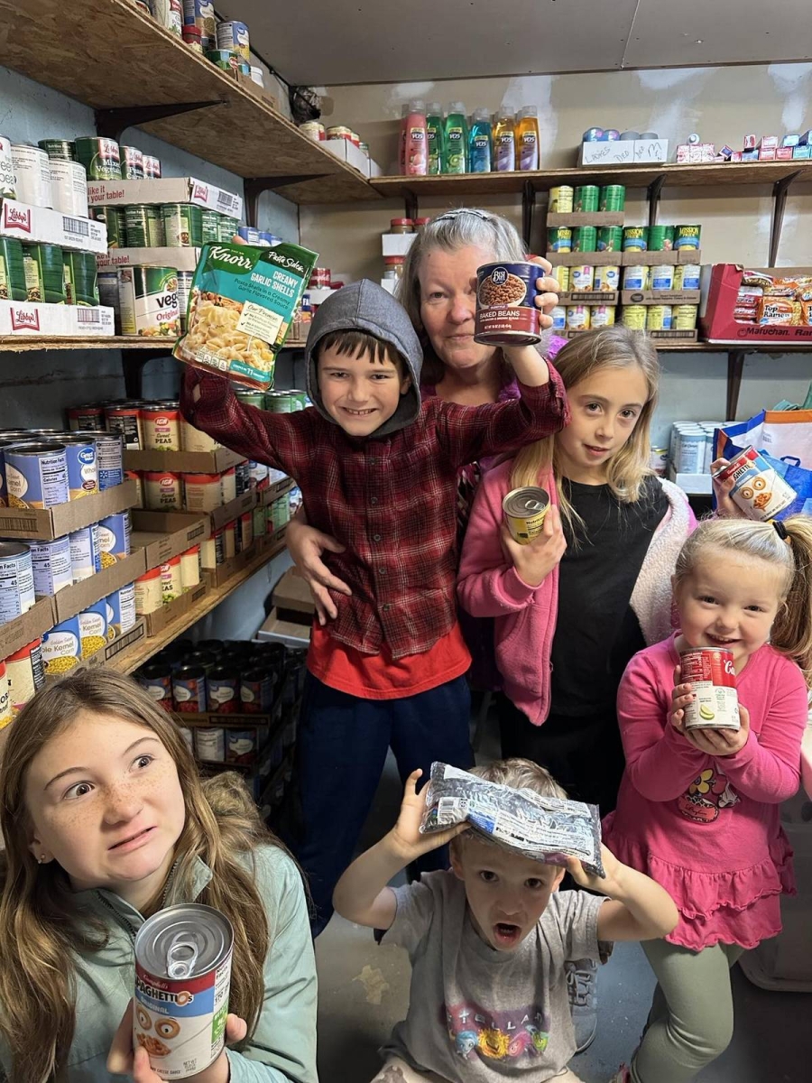 Children and an adult hold up cans of food.