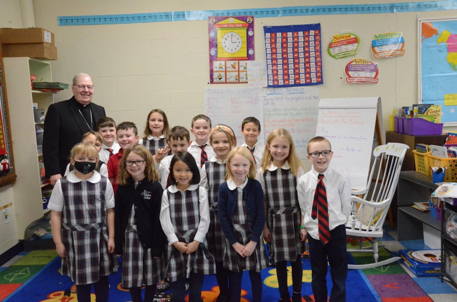 A group of students in uniforms pose with the bishop