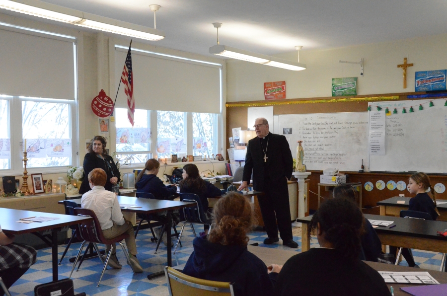 The bishop stands at the front of the classroom.