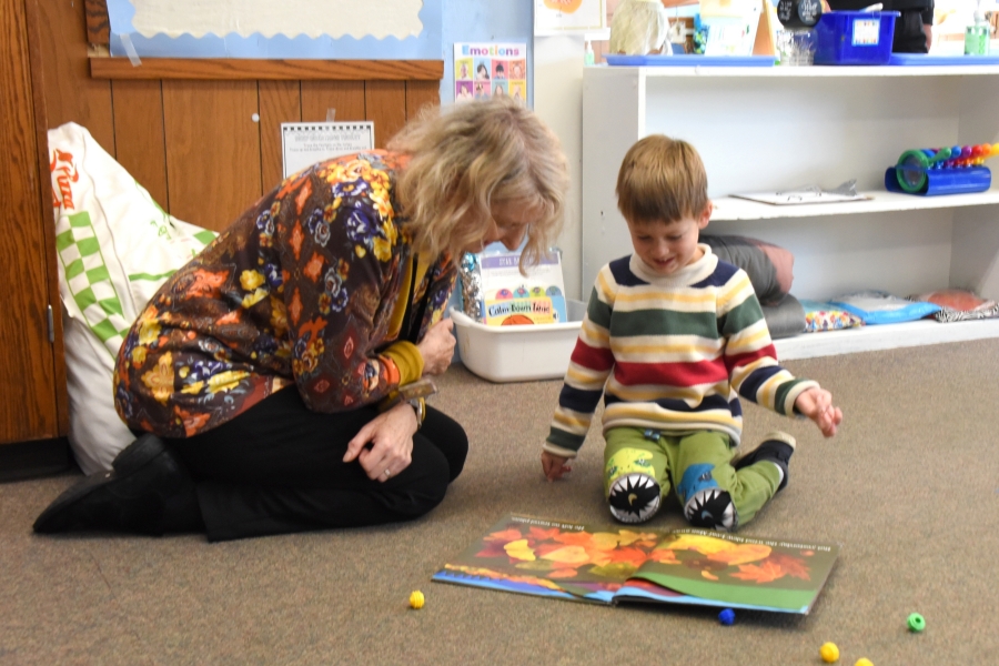 A foster grandparent reads a book with a preschooler.