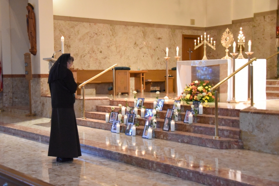 A Franciscan sister prays before the photos of the Lewiston shooting victims.