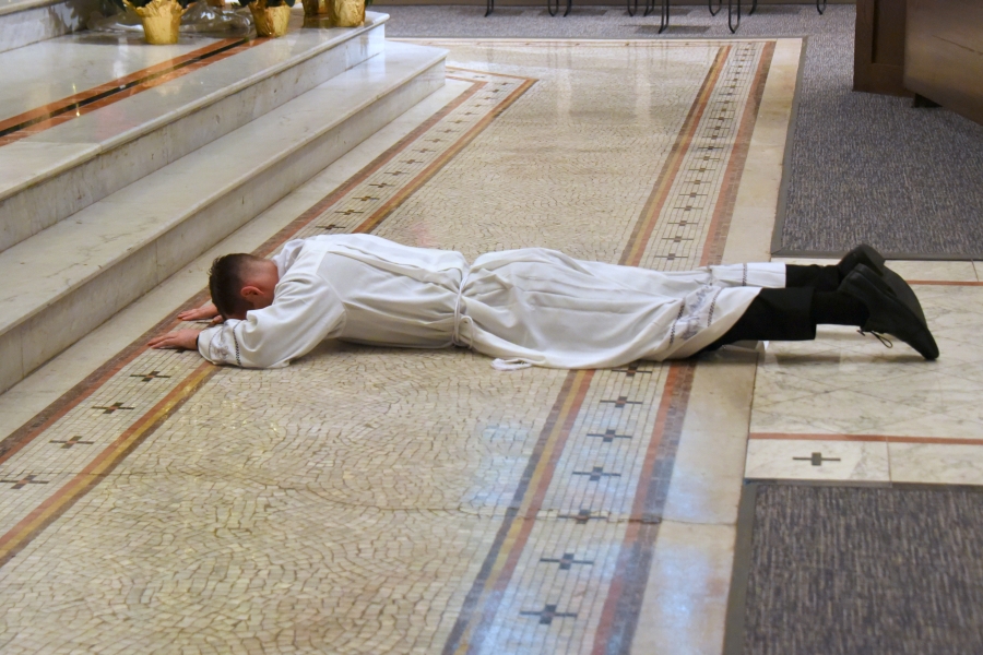 Lying prostrate while the Litany of Saints is sung.