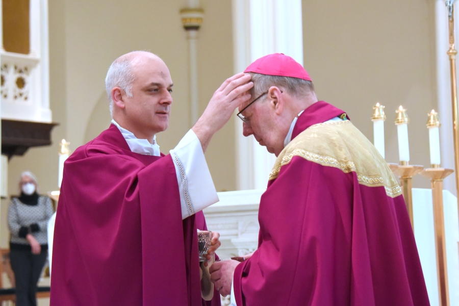 Father Seamus Griesbach places ashes on the forehead of Bishop Robert Deeley.