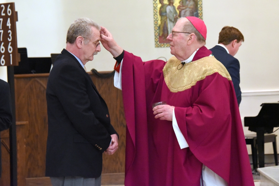 Bishop Deeley marks the forehead of a man with ashes.