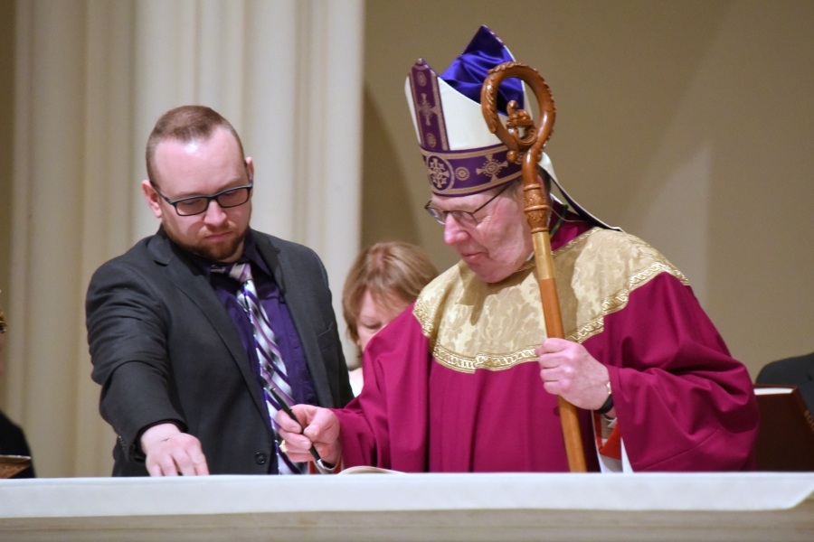 Bishop signs the Book of the Elect for Prince of Peace Parish.