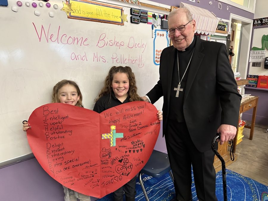 Bishop with student holding a heart shaped sign