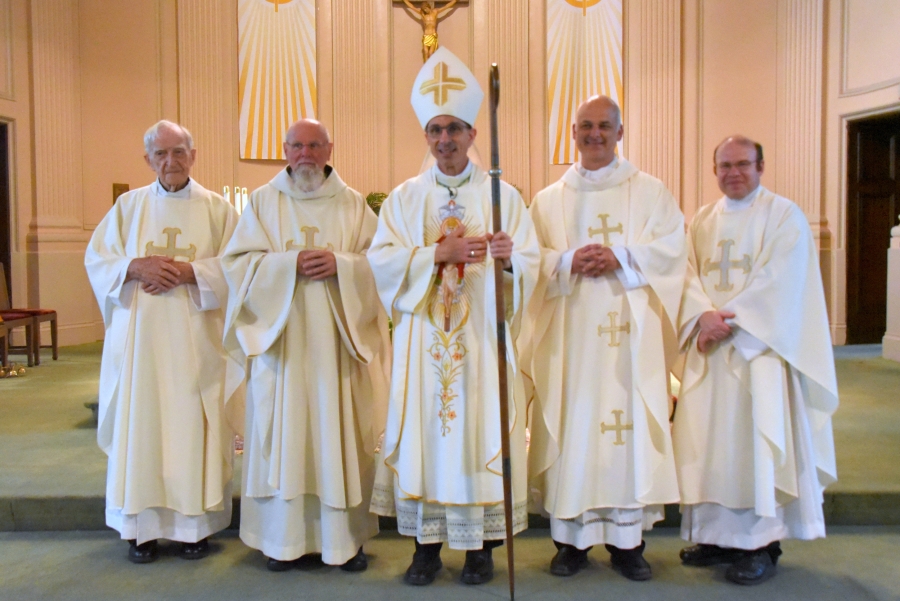 Spanish-speaking priests including Father Phil Tracy, Father Michael Sevigny, Bishop James Ruggieri, Father Seamus Griesbach, and Father Kevin Upham.