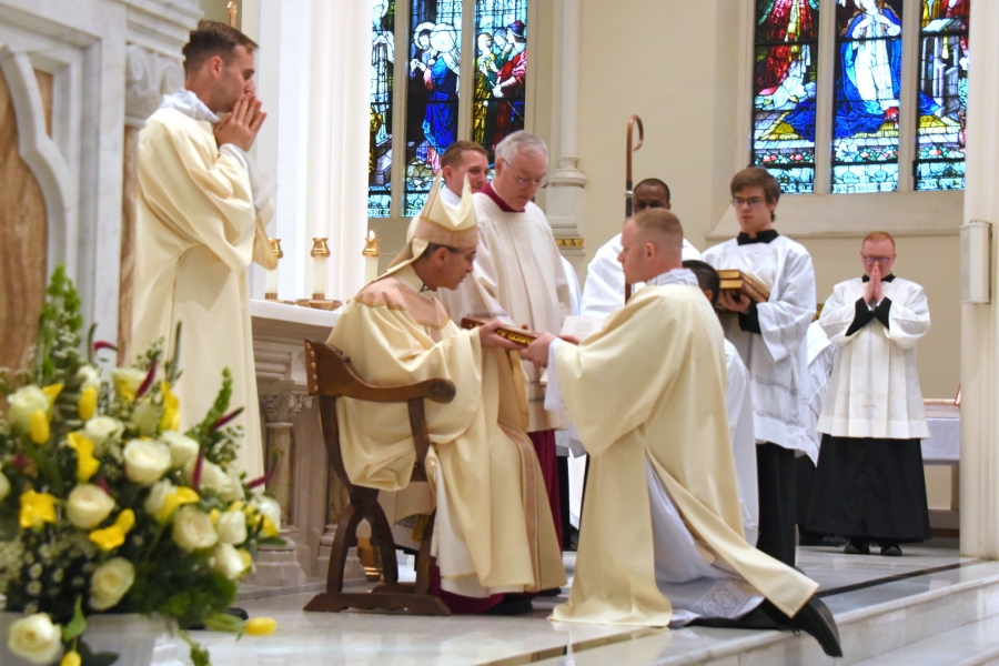 Bishop Ruggieri presents Deacon Donlon with the Book of the Gospels.