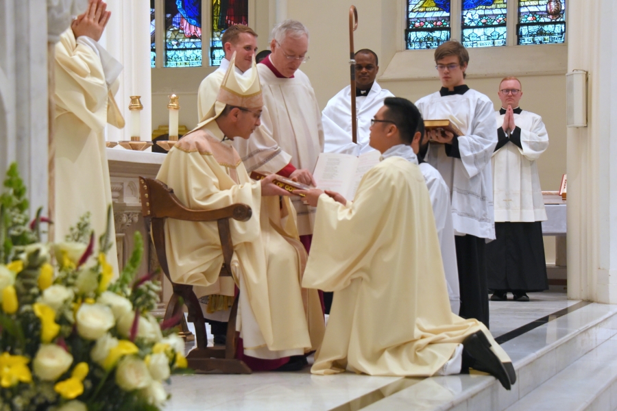 Bishop Ruggieri presents Thanh Duc Pham with the Book of the Gospels.