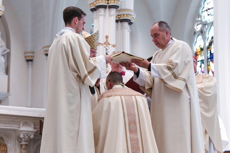 Two deacons hold the Book of the Gospels above Bishop Ruggieri's head.