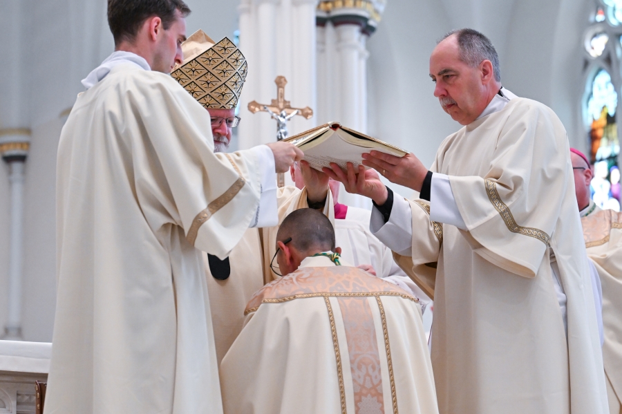 Deacons hold the Book of the Gospels over Bishop Ruggieri's head.