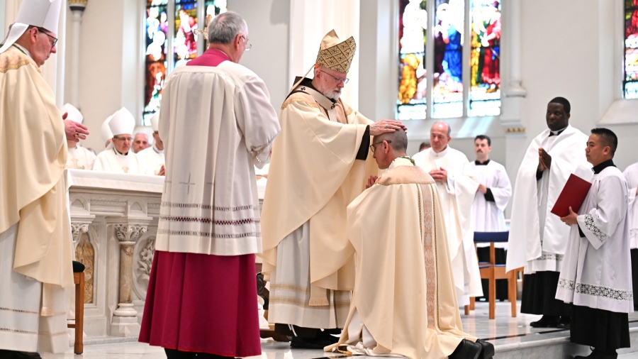 Cardinal O'Malley lays hands on Bishop Ruggieri, with Bishop Deeley and Msgr. Caron to his right.