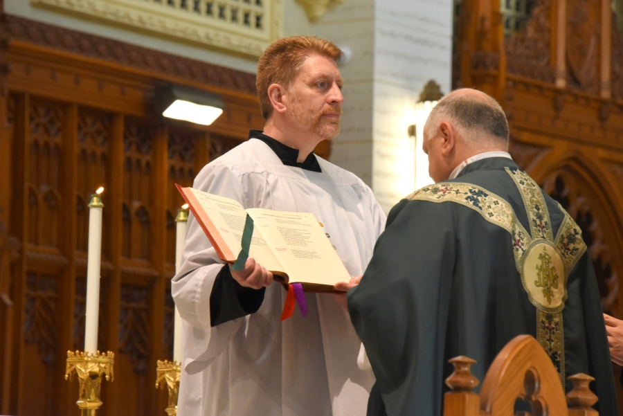Brian Wilson holds the Lectionary for Father Daniel Greenleaf.