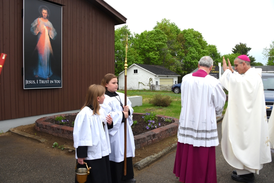 Bishop James Ruggieri blesses an image of Christ the Divine Mercy on the exterior of St. Martin of Tours Church.