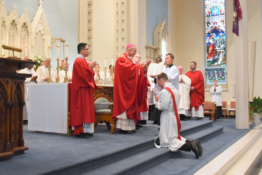 Bishop James Ruggieri prays the Prayer of Ordination with his hands outstretched over Deacon Valles.