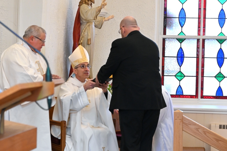 Doug Guerrette  is handed a Bible by the bishop.