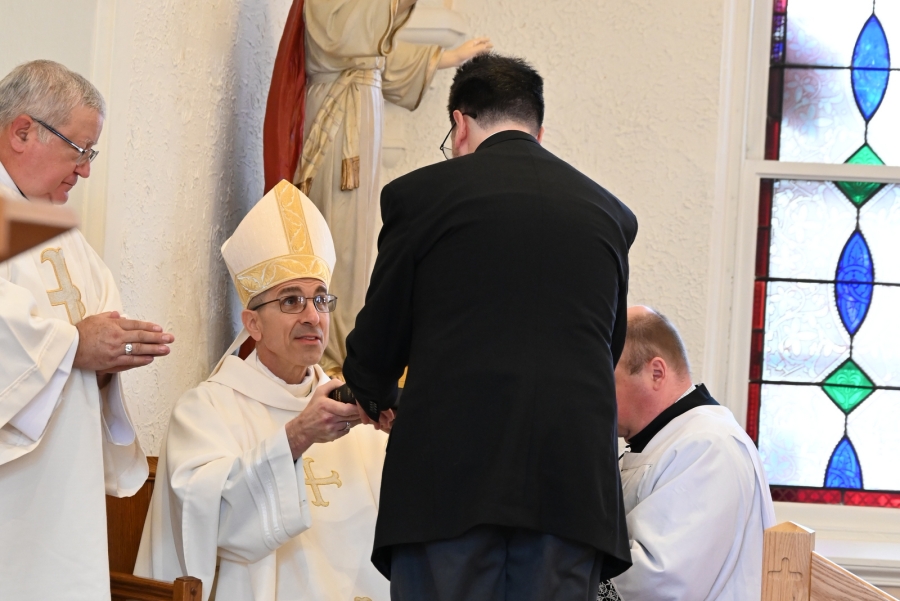 Sean Fidler is handed a Bible by the bishop.