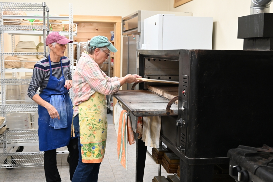 Anna Lake and Mariette Castonguay put bread in the oven.