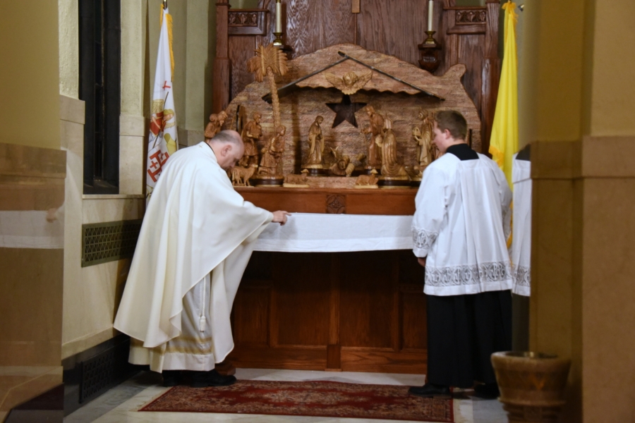 Father Daniel Greenleaf and an altar server dress the altar with a cloth.