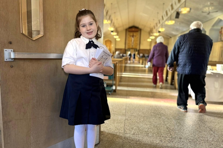 Little girl handing out bulleting before Mass at Holy Family Church in Sanford.