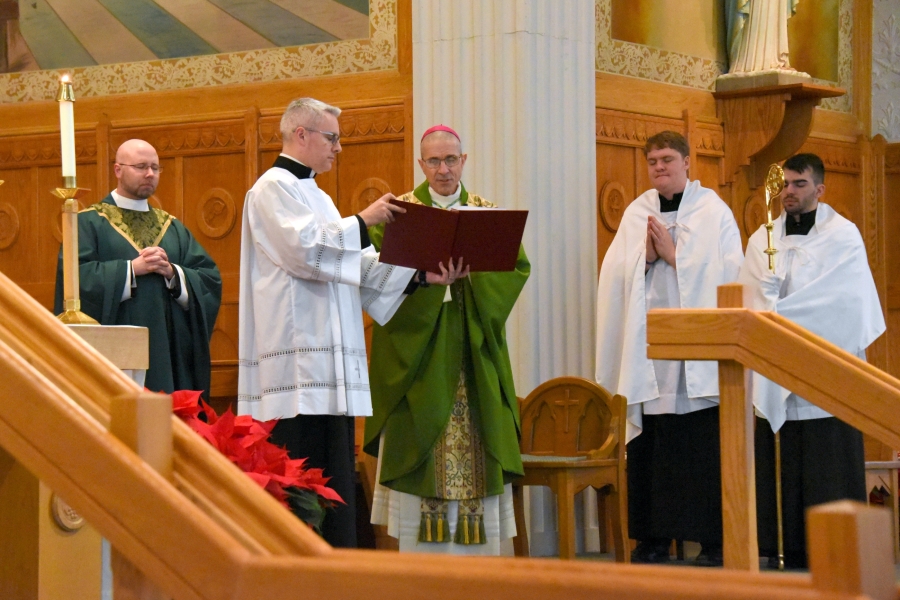 Bishop James Ruggieri praying with Deacon Luis Sanclemente holding the Mass book.