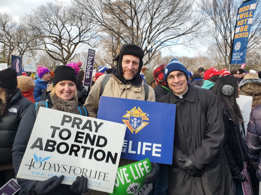 Three people outside holding signs